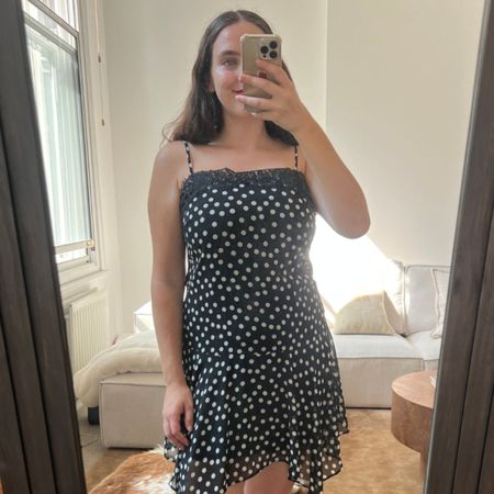 An image of Who What Wear UK fashion writer, Ava Gilchrist, wearing the viral M&S polka-dot lace-trim slip dress. She is a size M and wears it in a size 10. 