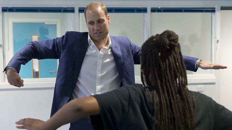 Prince William with arms extended attempting "The Wave" dance move.