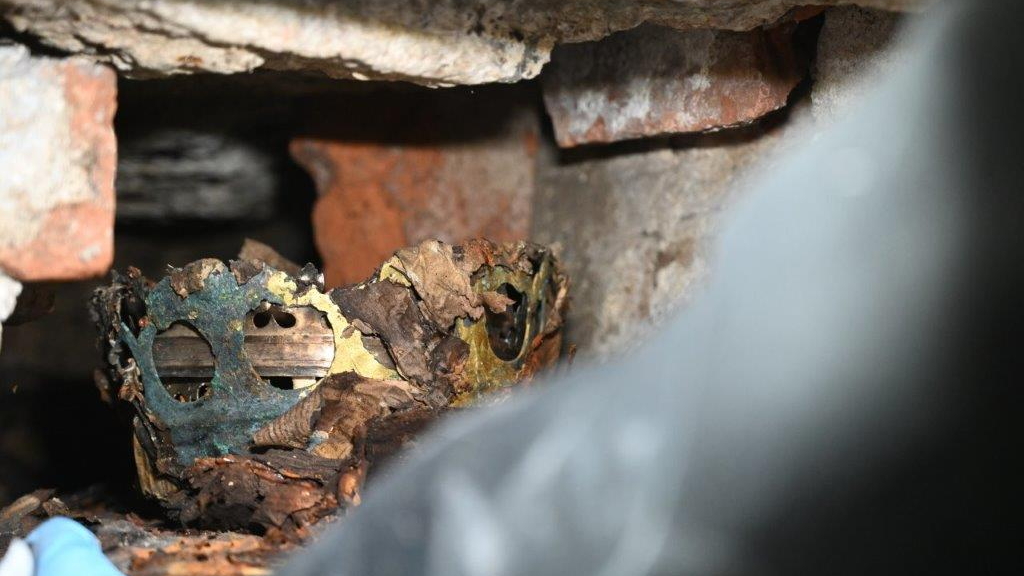 A tarnished gold crown in a hidden cavity of a brick wall