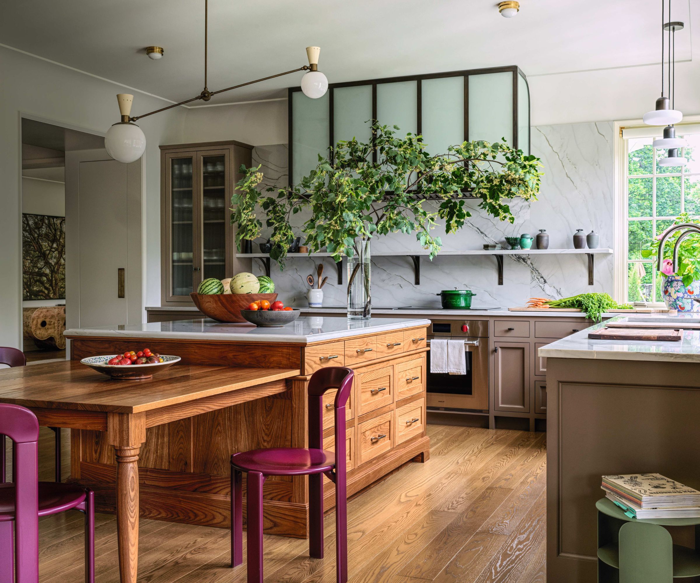 Brown kitchen with wooden island, white worktops and wooden dining table with pink chairs