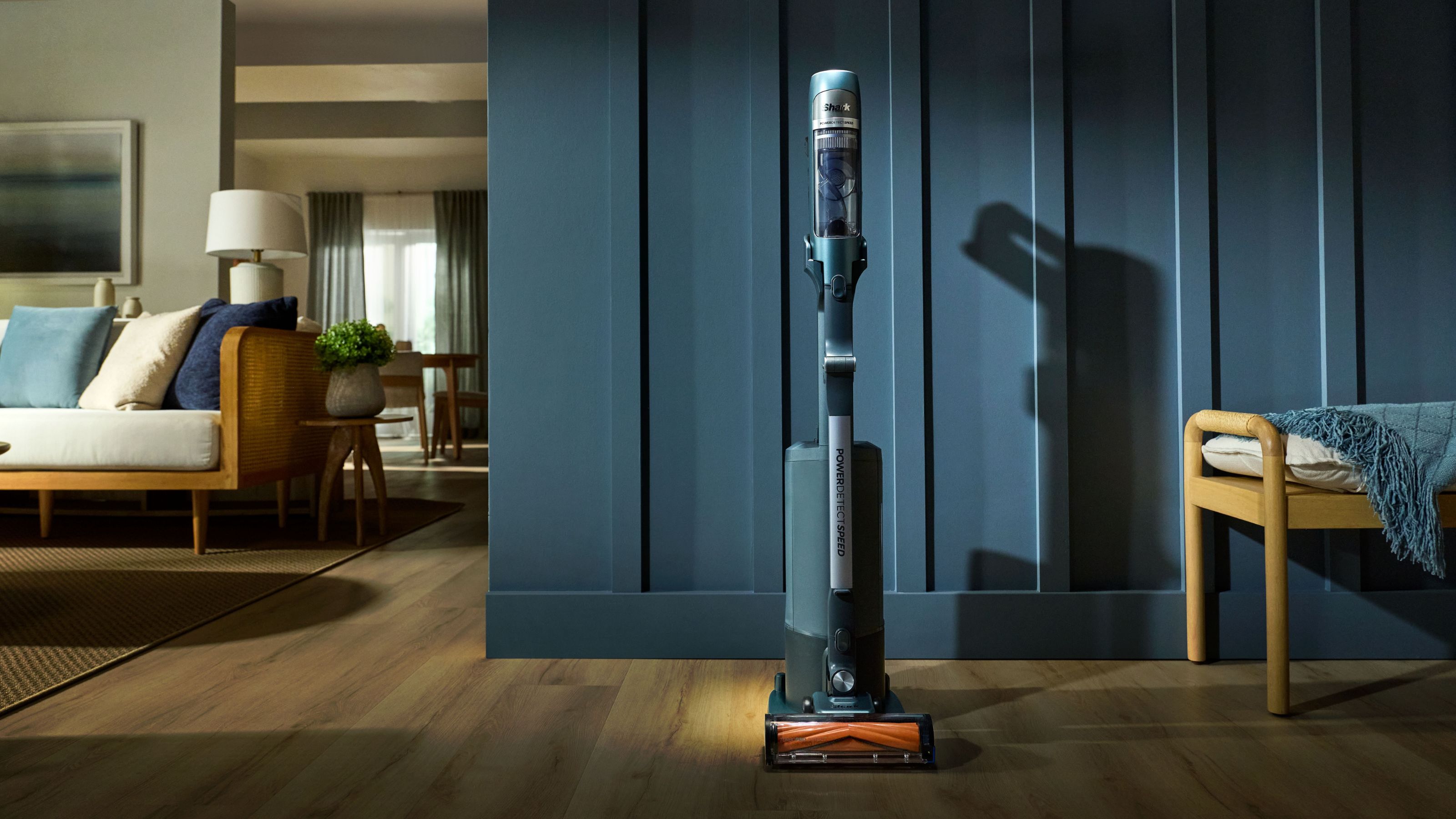 Shark luxe collection vacuum sitting on wooden floors in front of teal-coloured wall panelling