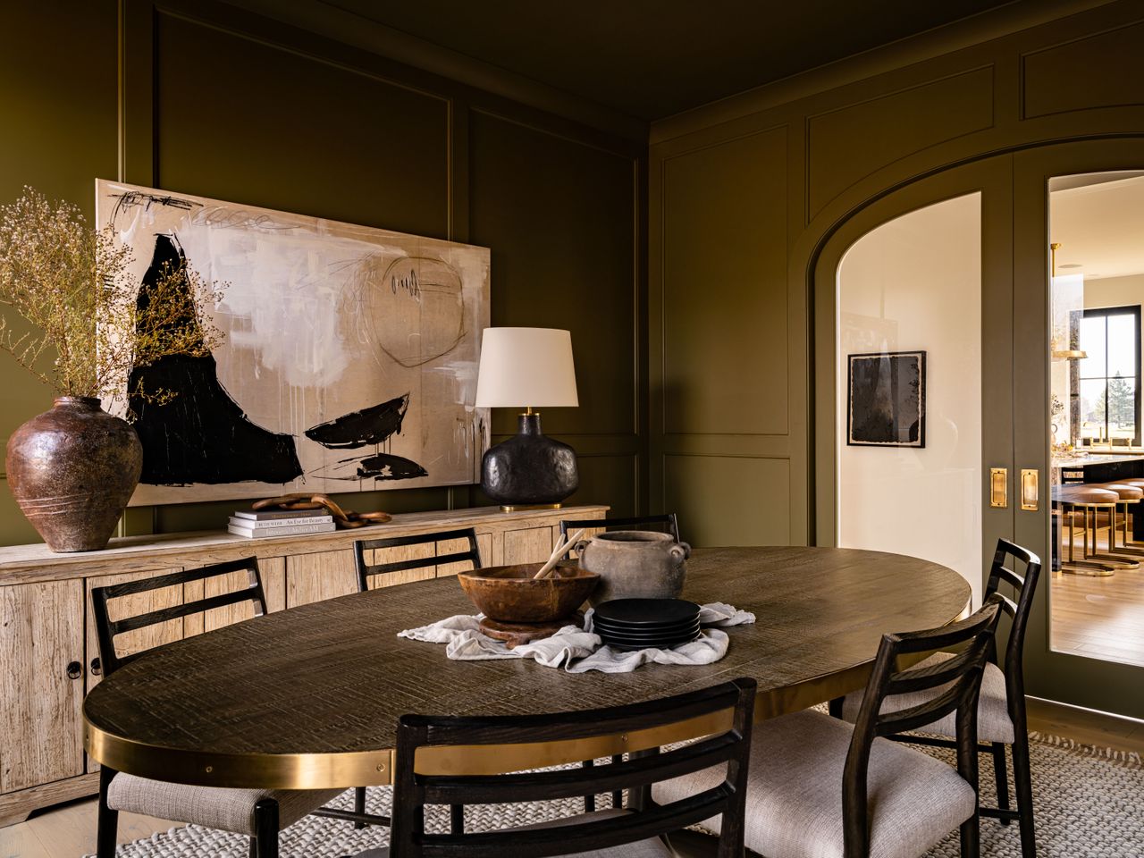 A dark green dining room with a gold oval dining table