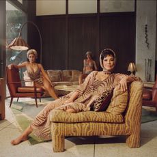 Roberto Cavalli x Skims campaign image of Kris Jenner lounging on a chair wearing a palm leaf-printed outfit and head scarf while Kim Kardashian sits on a chair in the back in a matching swimsuit.