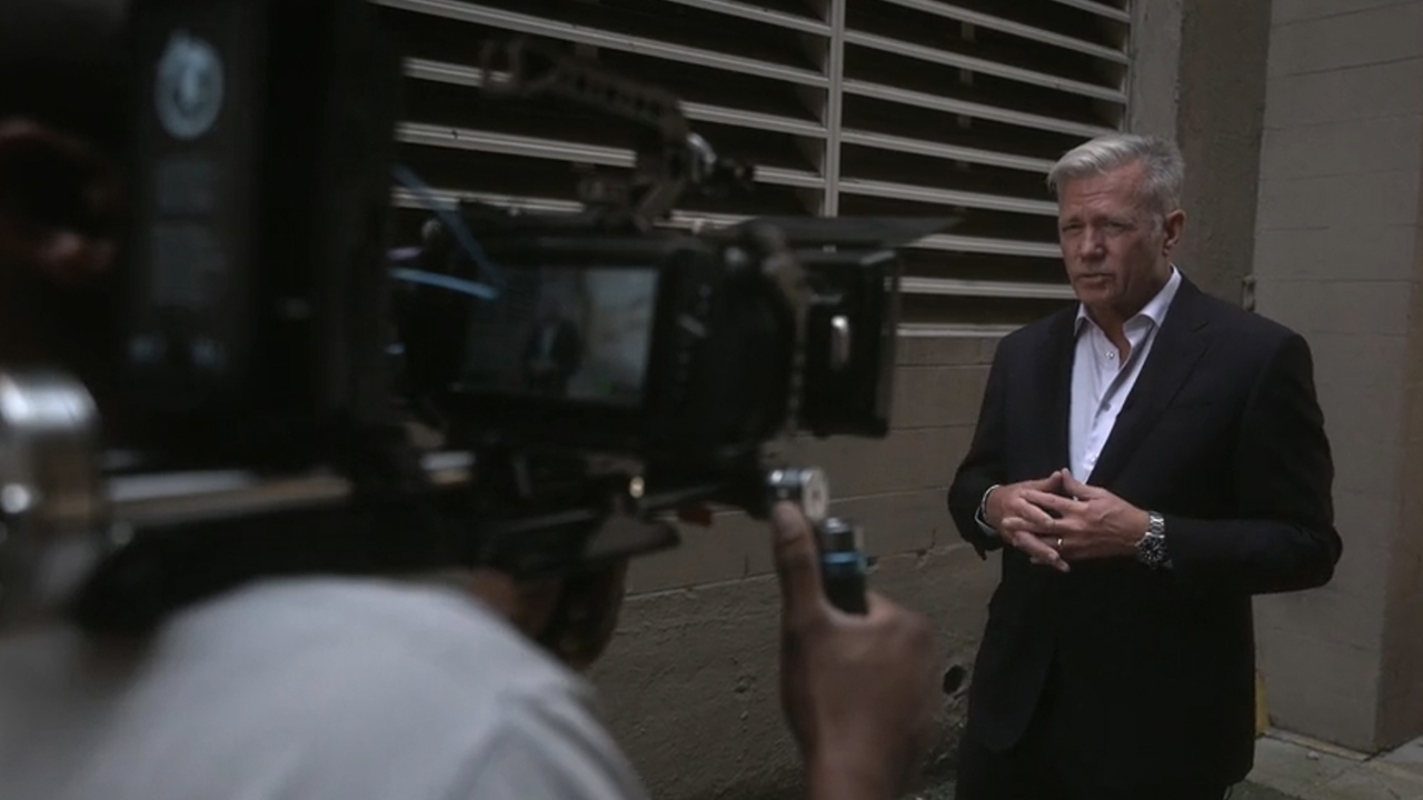 Chris Hansen looking at a TV camera in Predators. 