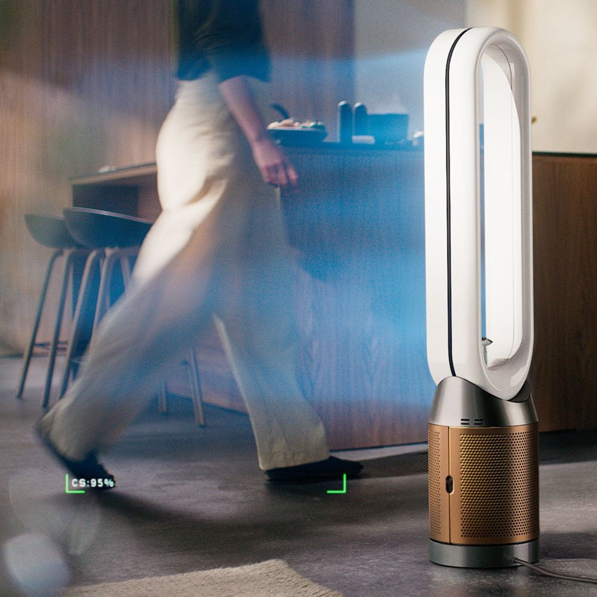Dyson Find+Follow air purifying fan next to a kitchen island, with a person walking in front of it