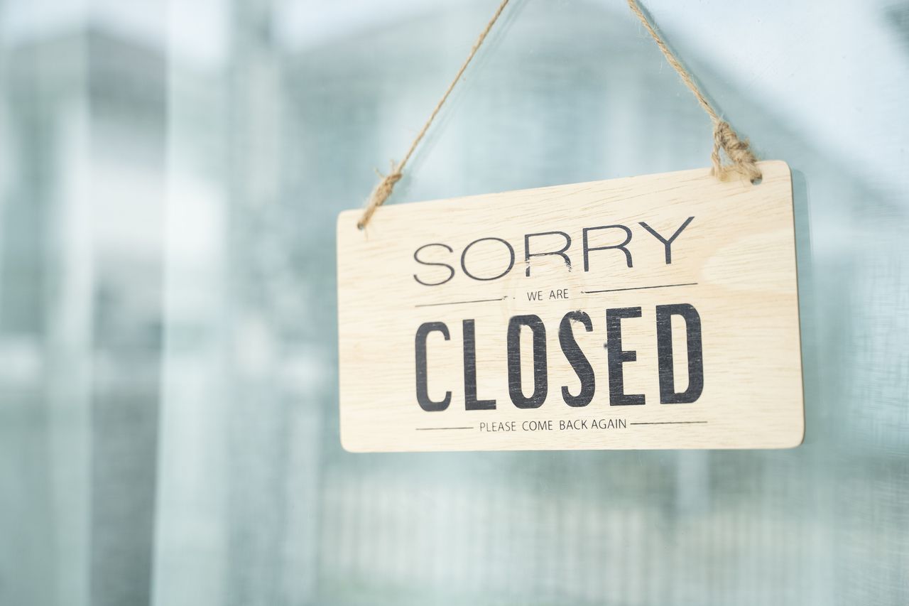 sorry we&#039;re closed sign hanging on a glass door