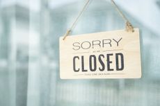 sorry we're closed sign hanging on a glass door