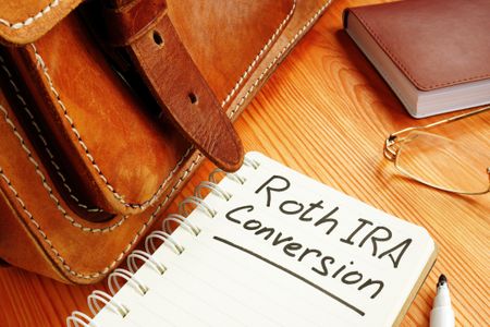 Roth IRA conversion memo near retro briefcase and glasses