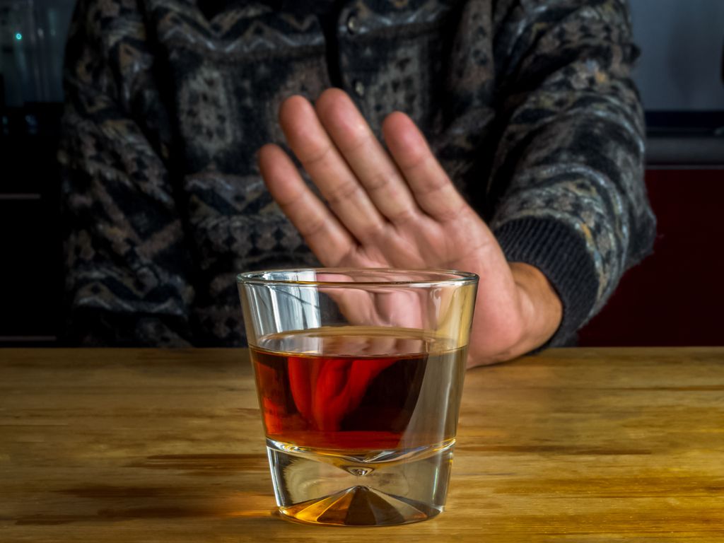 man pushing away glass of alcohol