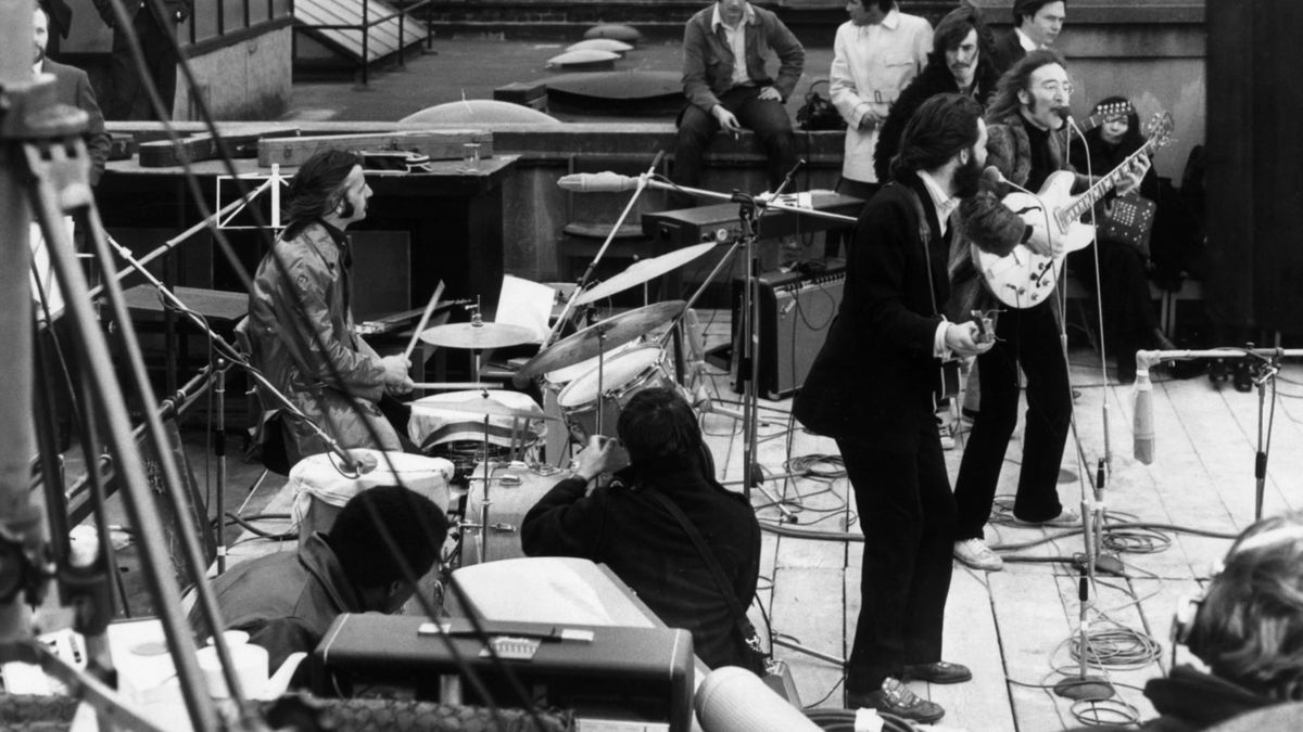 30th January 1969: British rock group the Beatles performing their last live public concert on the rooftop of the Apple Organization building for director Michael Lindsey-Hogg&#039;s film documentary, &#039;Let It Be,&#039; on Savile Row, London, England. Drummer Ringo Starr sits behind his kit. Singer/songwriters Paul McCartney and John Lennon perform at their microphones, and guitarist George Harrison (1943 - 2001) stands behind them. Lennon&#039;s wife Yoko Ono sits at right.