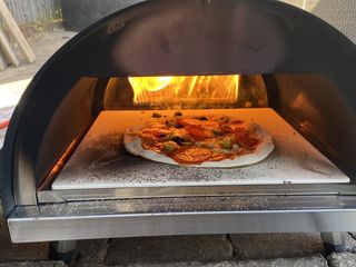 Close up of a pizza cooking in the Woody pizza oven using the gas