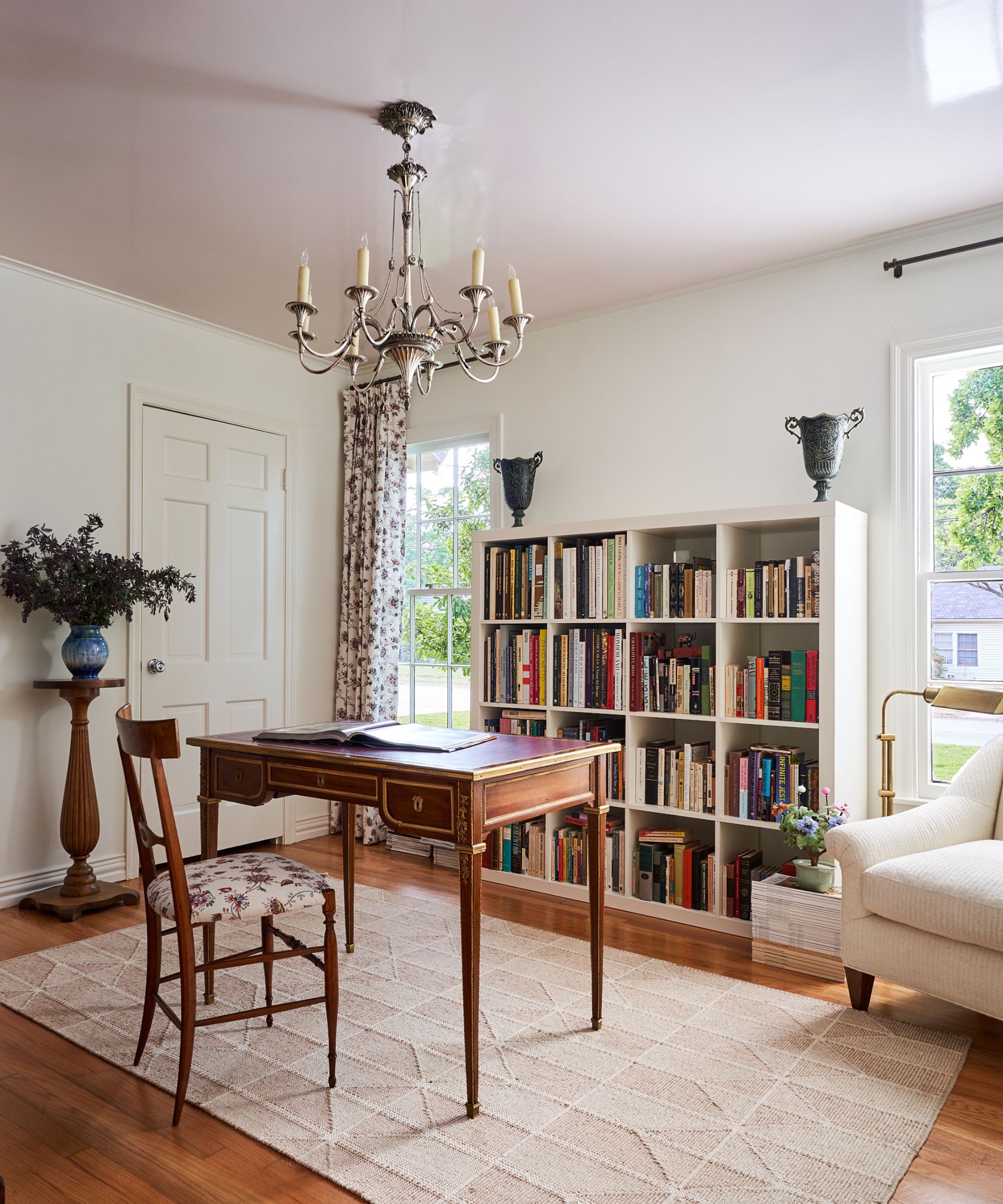 a white painted home office with antique furniture and a glossy pale pink ceiling