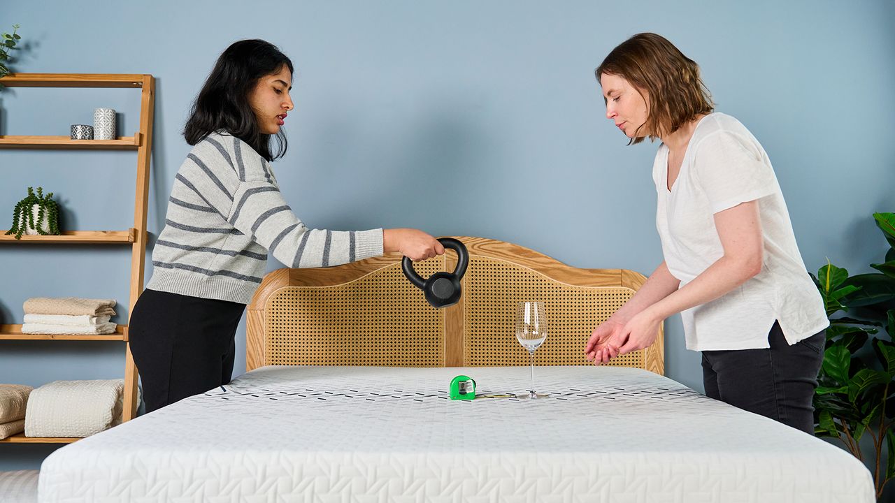 Two Tom's Guide mattress testers dropping a weight next to a wine glass to measure how well the Nectar Ultra Hybrid performs in motion isolation tests