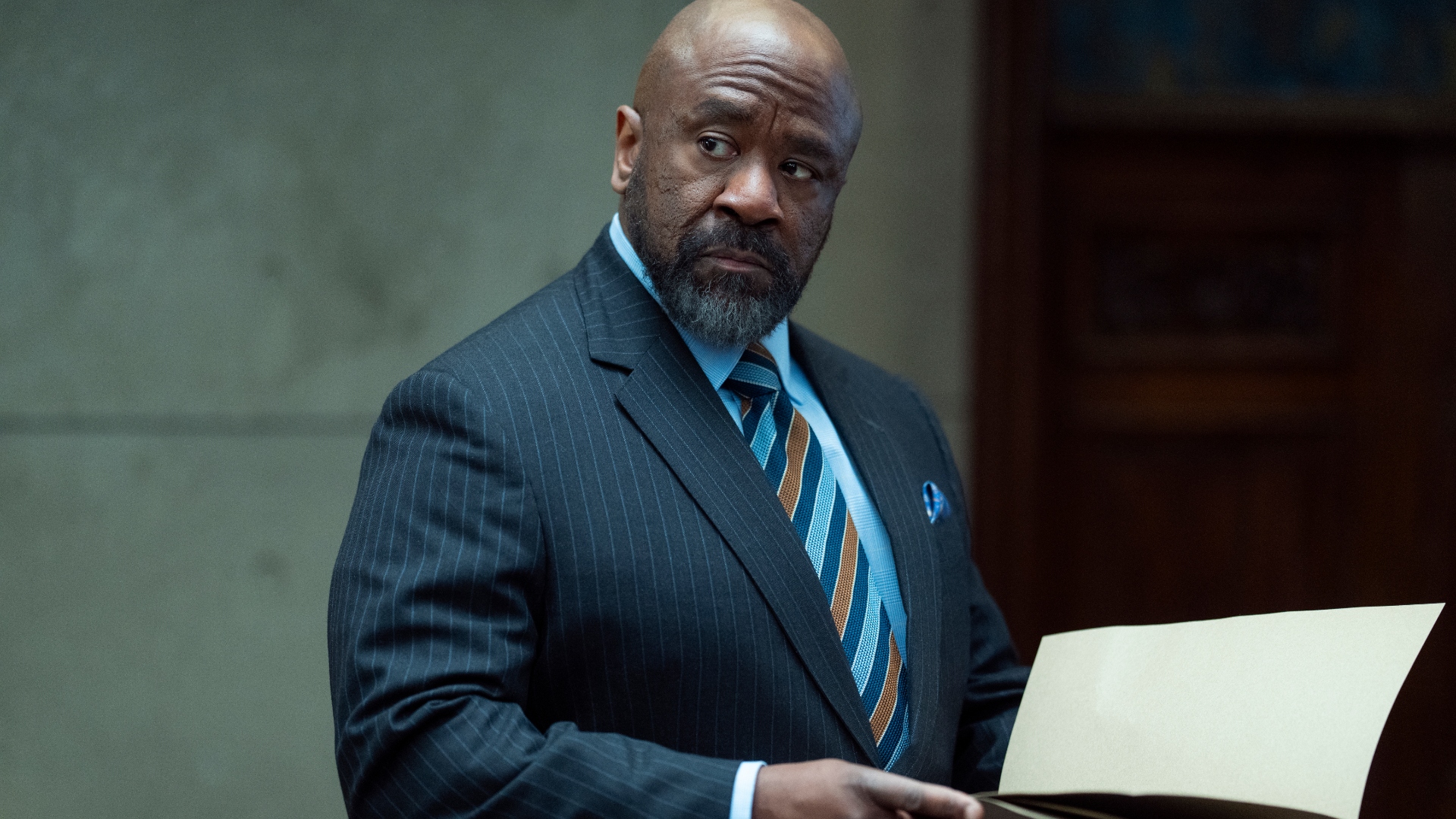 Kofi looks at a file in Hostage