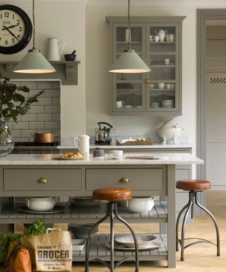 pale green metal pendant lights hung above wooden island with open shelving below