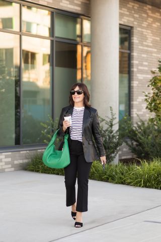 A Nordstrom buyer wearing a striped T-shirt with a leather blazer and a green handbag.