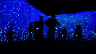 A group of people in a darkened room with a blue, snowy background.