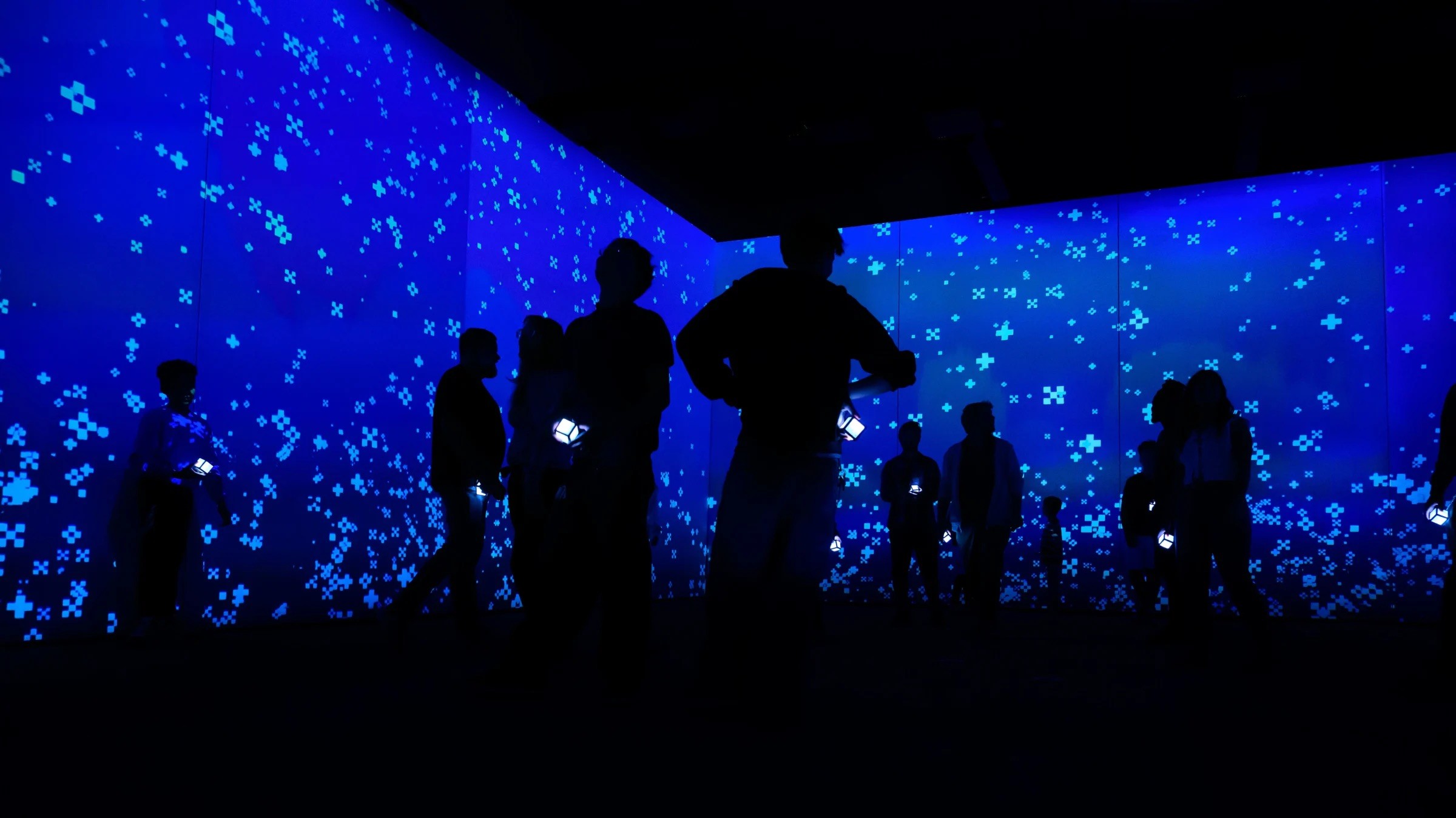 A group of people in a darkened room with a blue, snowy background.