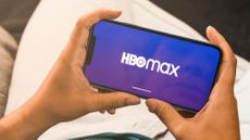 Hands holding smartphone with HBO Max logo in landscape