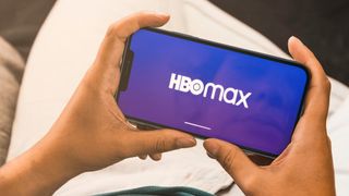 Smartphone in iemands handen met het HBO Max-logo op het scherm