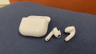AirPods 3 out of their case on a blue pillow