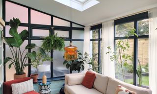 Blue painted conservatory with black painted uPVC window frames and 70s glass ceiling pendant lighting