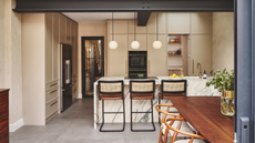 open plan kitchen in a warm, beige color with a central island with bar seating and a banquette seating area off to the side