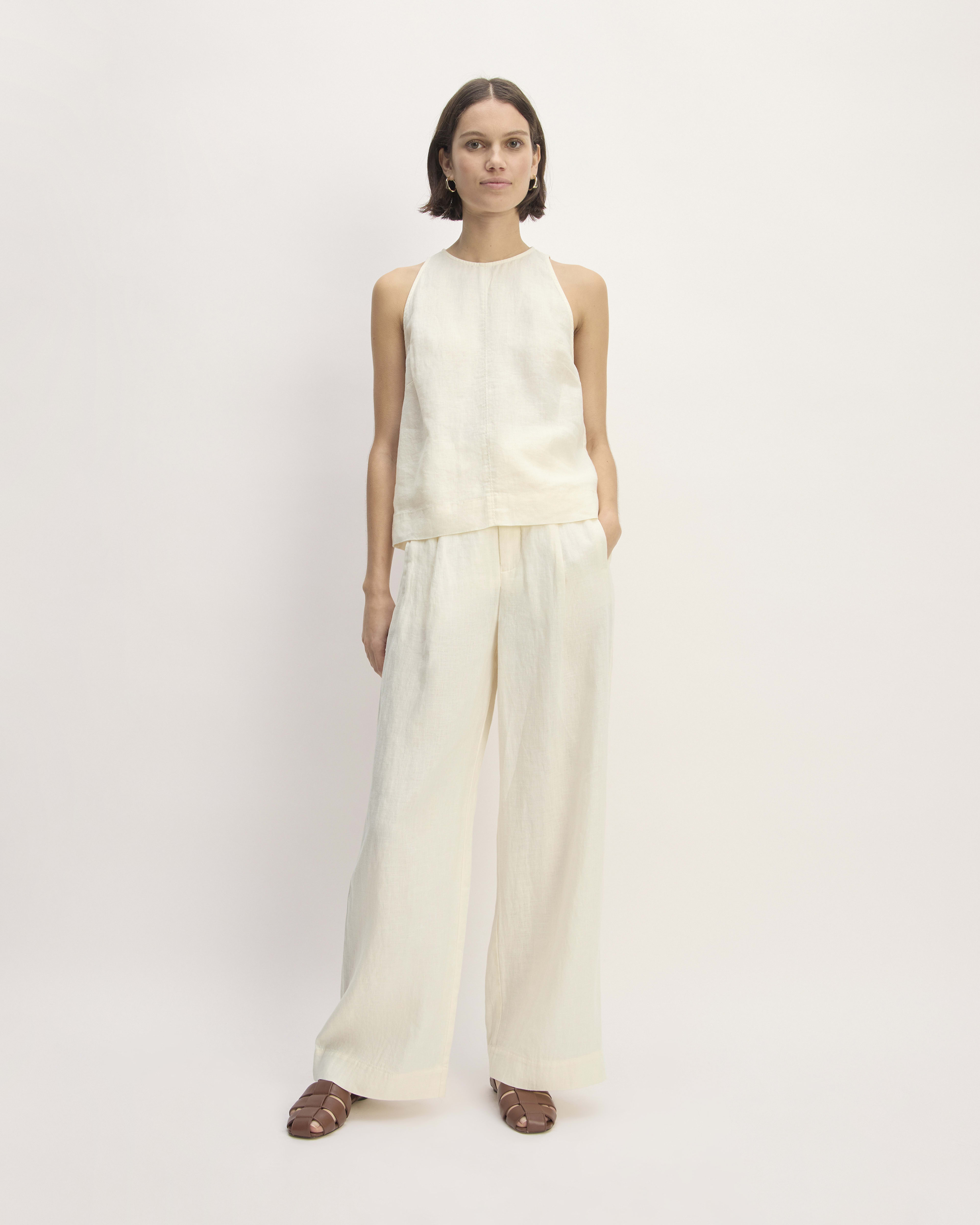 a model wears a white tank top and matching linen trousers