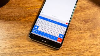 AnySoftKeyboard on an Android phone kept on a wooden table.