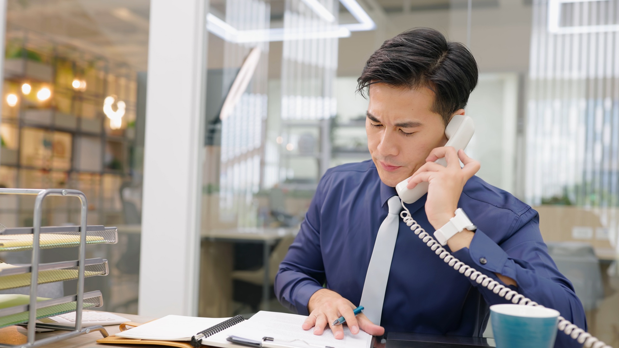 A young man answers the phone in an office.