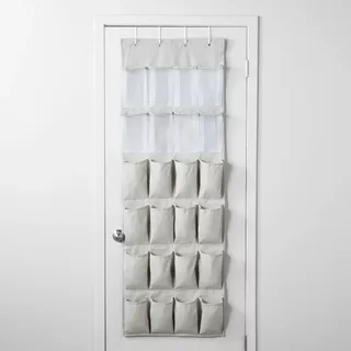 A grey fabric over-the-door shoe organizer with 24 pockets hung on the back of a white door