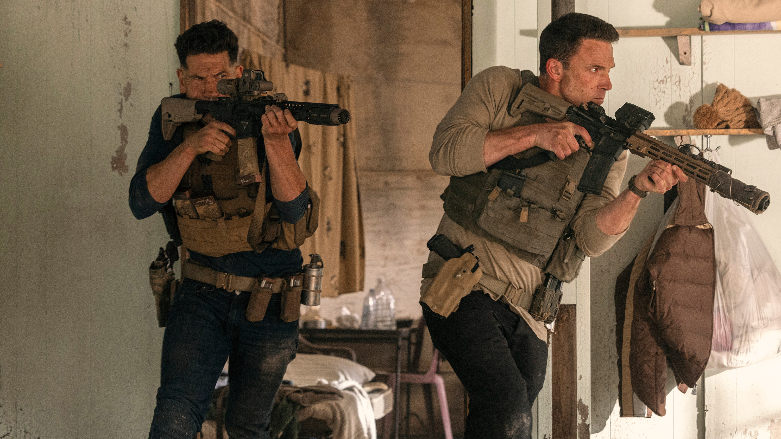L-R: Brax (Jon Bernthal) and Christian Wolff (Ben Affleck) armed with assault rifles in a scene from "The Accountant 2"