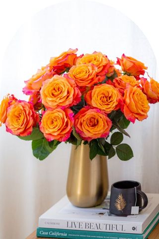 A bouquet of yellow and pink roses in a gold vase.