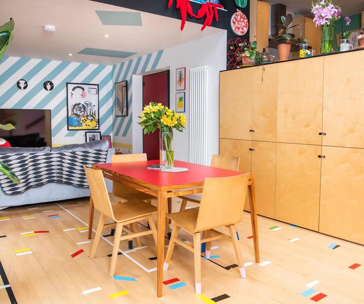 A dining area with wooden dining table and chairs with pink walls
