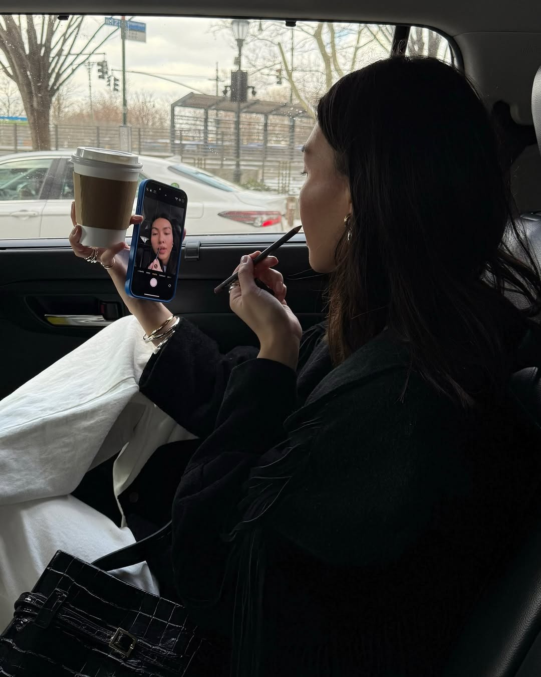 A woman applying lip liner in the car.