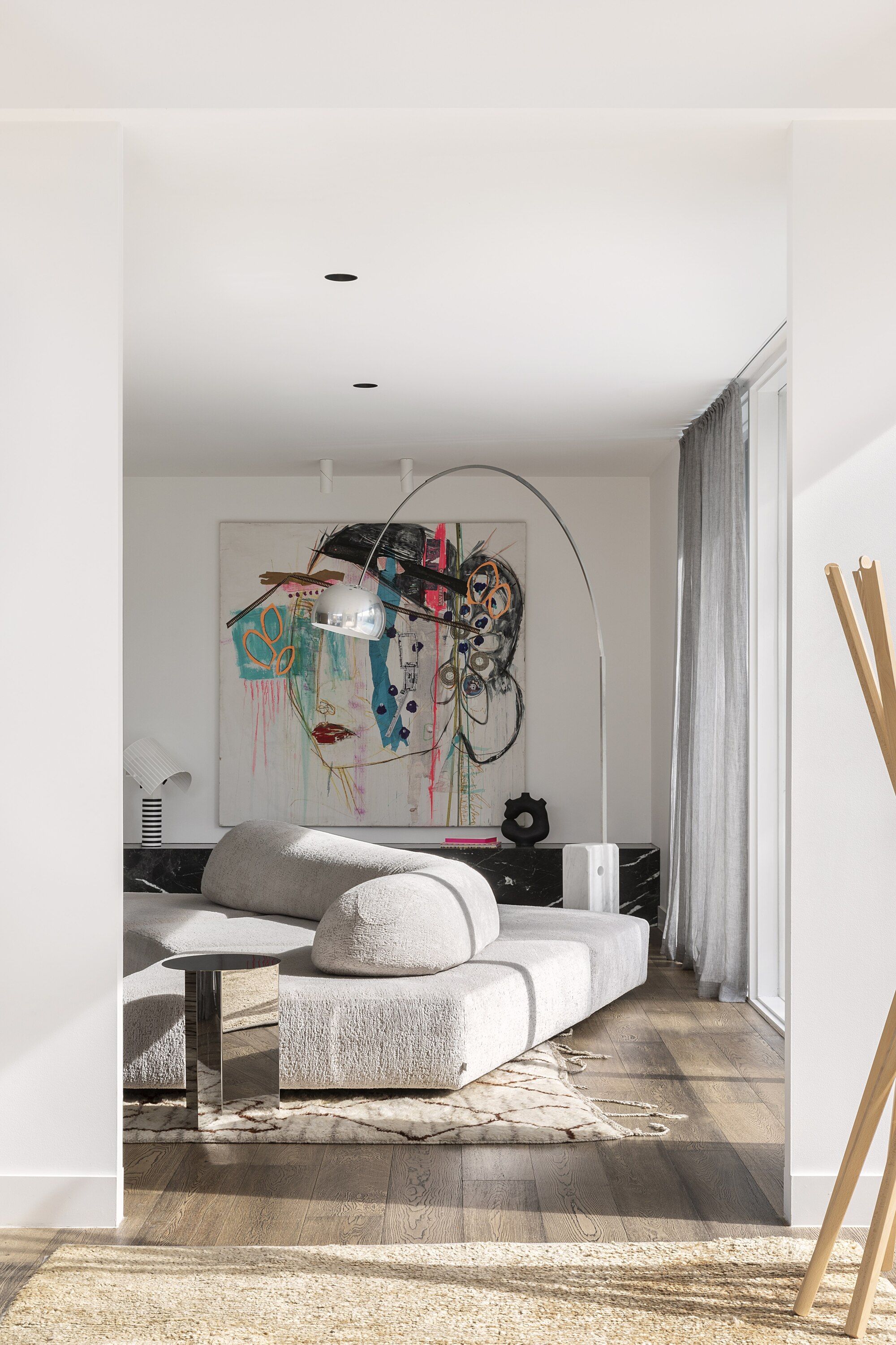 modern living room with floating angular sofa, large artwork, rug, and arching mid-century style floor lamp