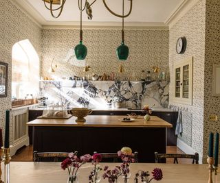 bright and open kitchen with floral wallpaper and a dark painted kitchen with purple veined marble counters and backsplash