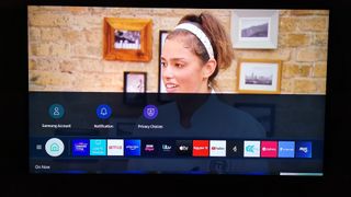 The AU9000 displaying a TV show with a woman and also showing the app icons.
