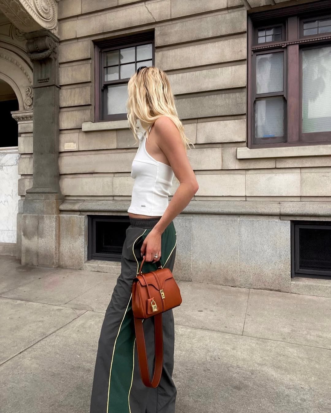 influencer Megan Adelaide wearing a white tank top with grey and green track pants and carrying a brown leather Celine handbag