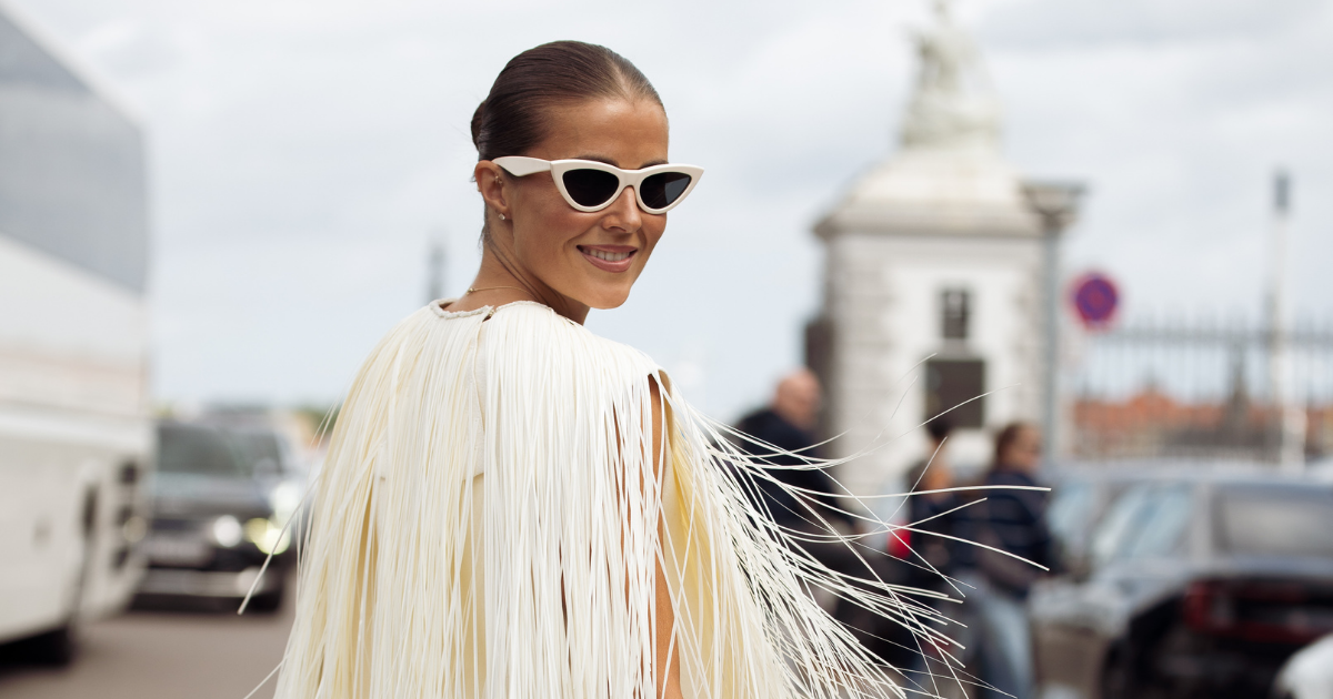 Fragrance primer - Nina Sandbech wears white dress with straws, white high heels and animal print or snake print bag outside MKDT Studio show during Copenhagen Fashion Week day three 