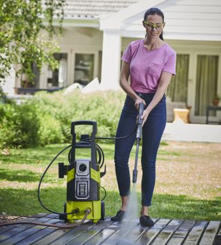 Woman cleaning deck with Ryobo RPW120b pressure cleaner