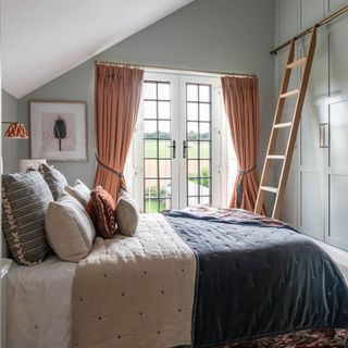 Eaves bedroom with double French doors and floor-to-ceiling wardrobes with library ladder