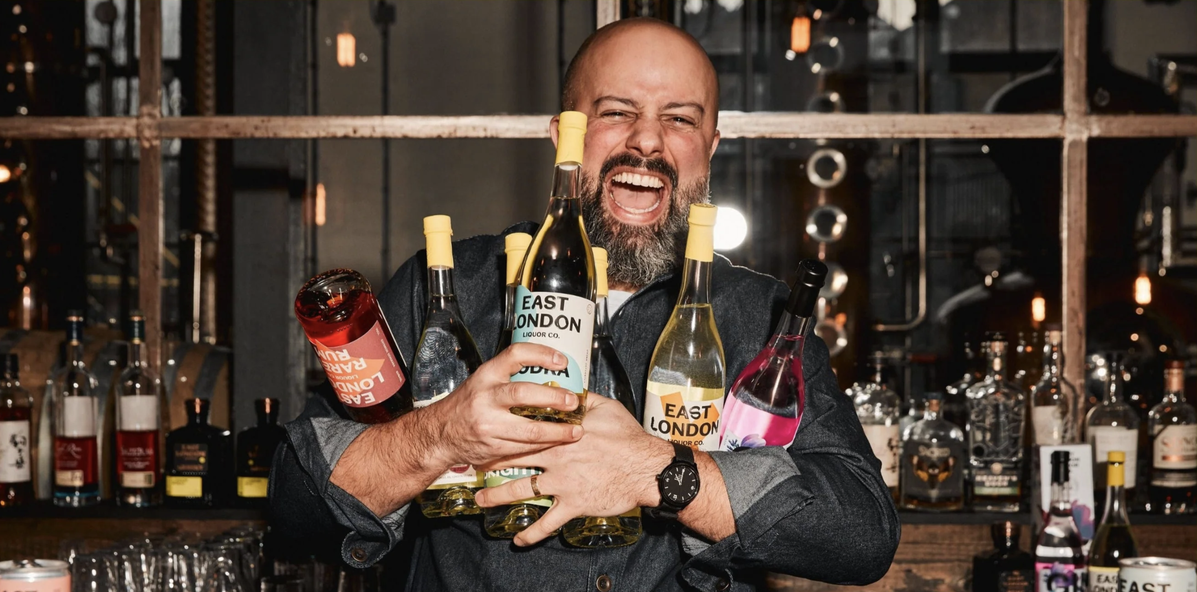 an image of one of the distillers at East London Liquor Company holding bottles from each of the distillery's range