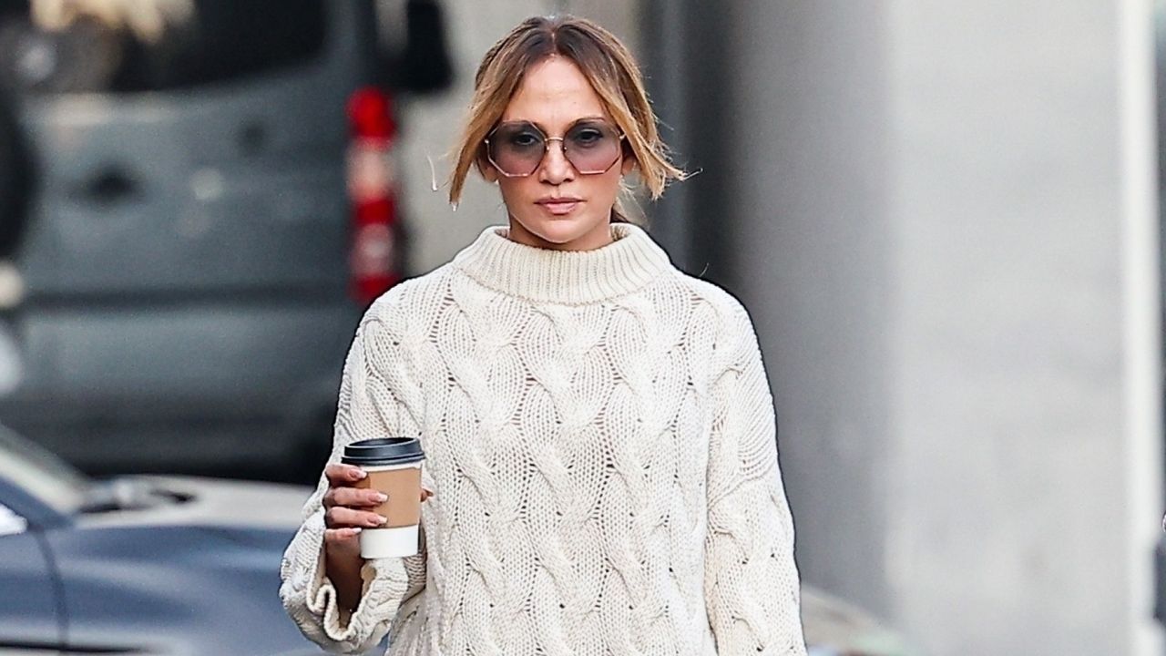 Jennifer Lopez walking in Los Angeles wearing a cable knit sweater with wide leg jeans and uggs