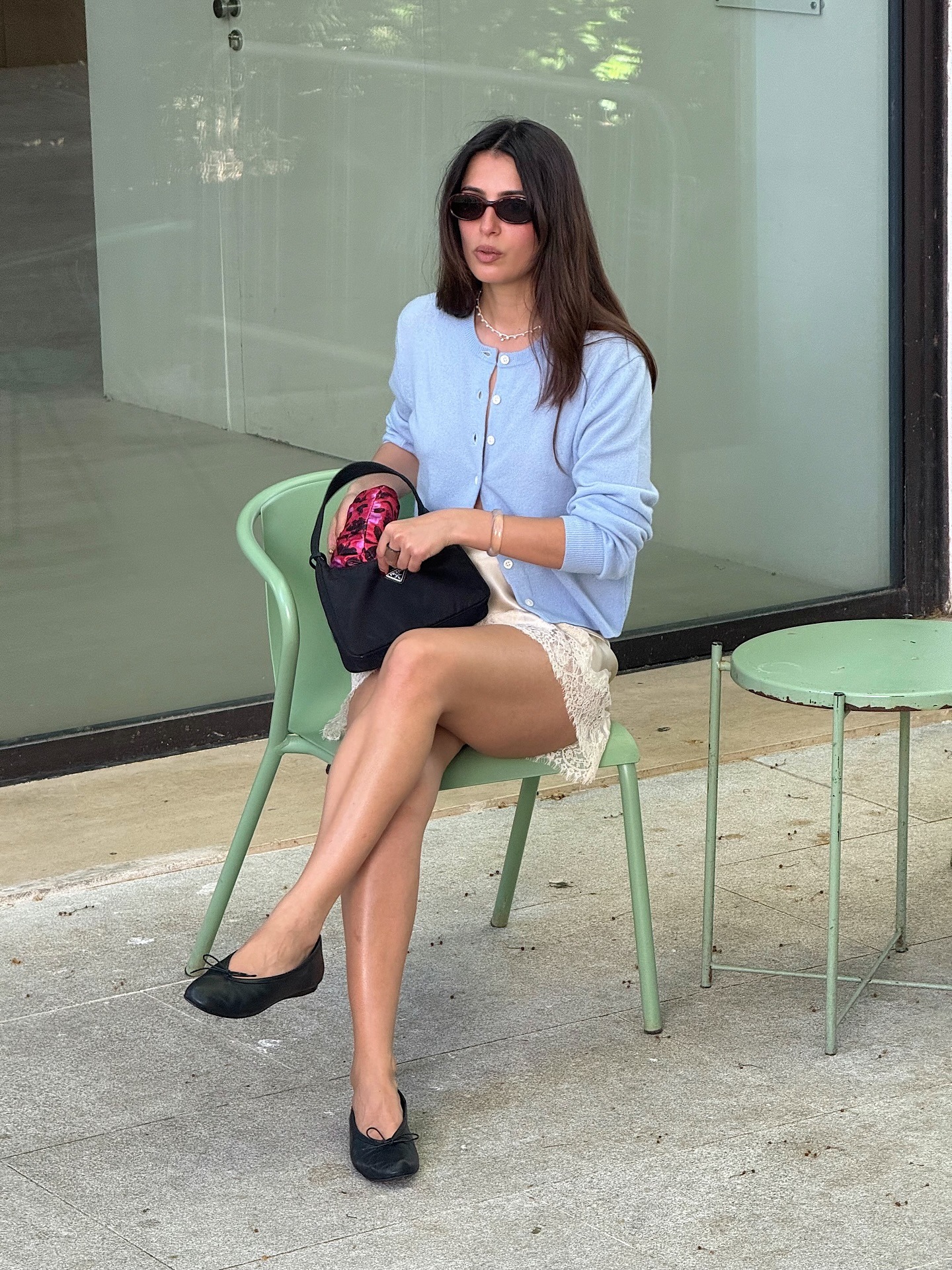 Woman in a cardigan, lace shorts, and ballet flats.