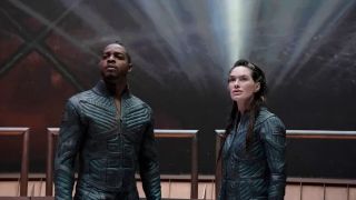 Stephan James (L) as Halan and Lena Heady (R) as Aster stand in front of the backdrop of space in "Beacon 23" season 2