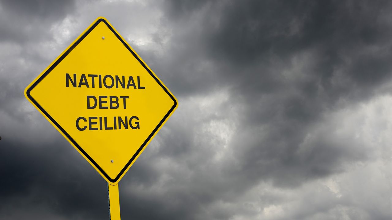 A caution sign reads &quot;National Debt Ceiling&quot; against the backdrop of a stormy sky.