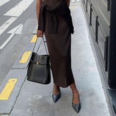 Woman wears brown skirt and black bag