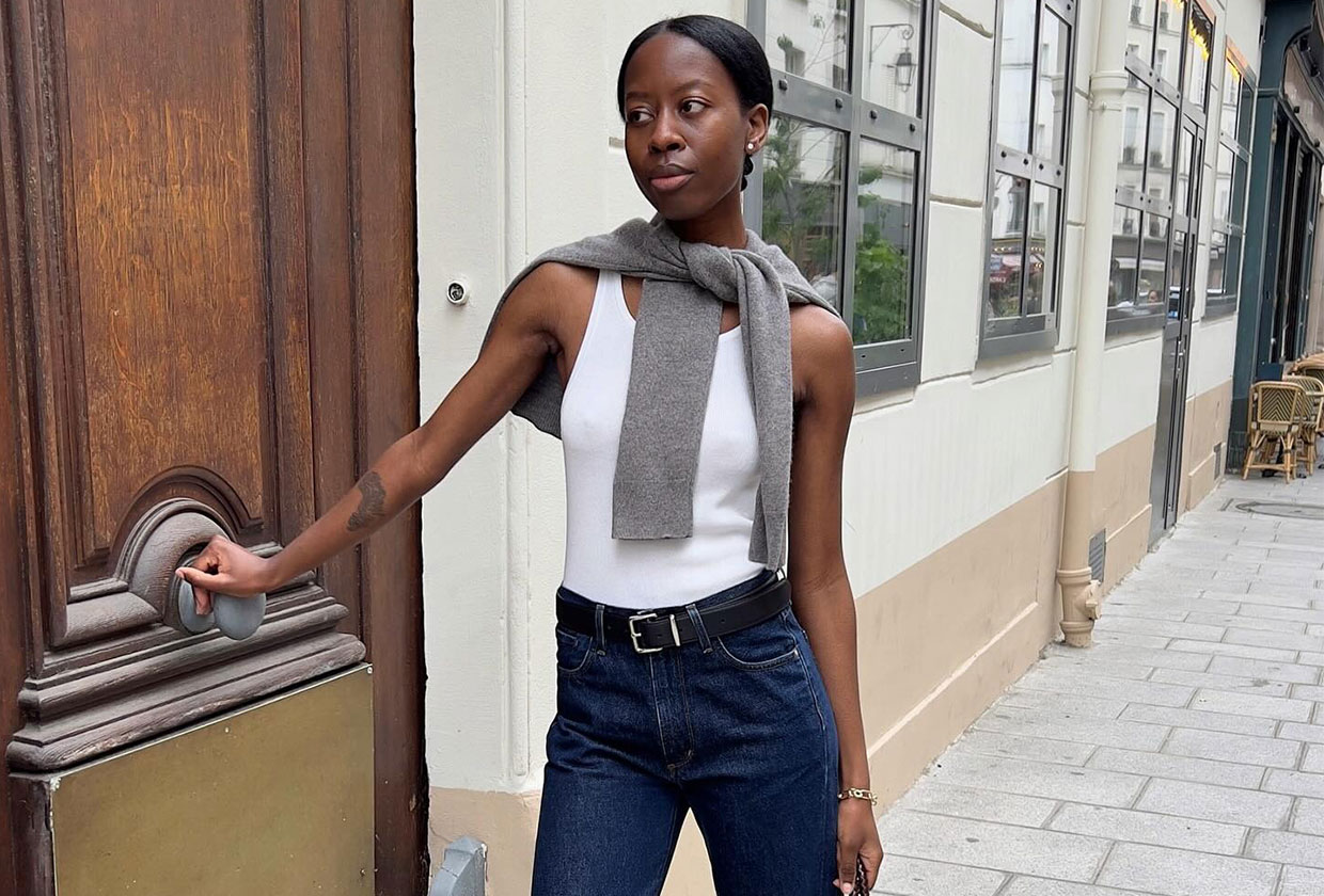 A French woman wearing a white tank and jeans.