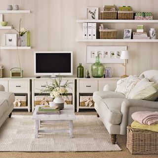 A neutral living room with wall of storage units and floating shelves